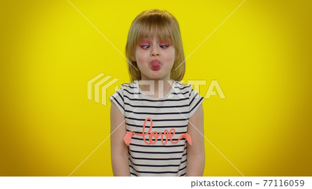 Funny child kid girl making playful silly facial expressions and grimacing, fooling, showing tongue 77116059