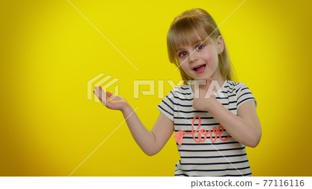 Little kid child girl showing thumbs up and pointing at left on blank space on yellow background Little kid child girl showing thumbs up and pointing at left on blank space on yellow background 77116116