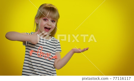 Funny child girl showing thumbs up and pointing empty place, advertising area for commercial text Funny child girl showing thumbs up and pointing empty place, advertising area for commercial text 77116117