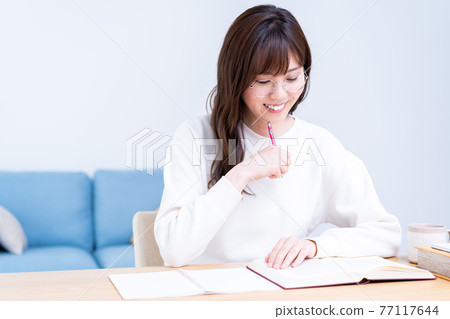 戴眼鏡在客廳學習的年輕女子 戴眼鏡在客廳學習的年輕女子 77117644