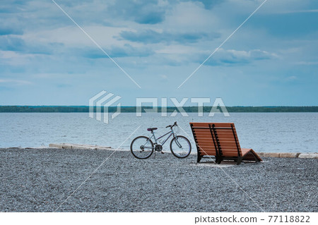 Retro styled photo of bicycle near bench on beach. 77118822