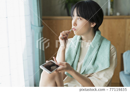 一個女人一邊刷牙一邊看手機 一個女人一邊刷牙一邊看手機 77119835