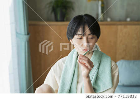 A woman brushing her teeth after taking a bath 77119838