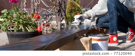 Real woman paints a board on the street. Rural life. DIY 77120040