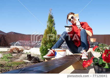 Real woman paints a board on the street. Rural life. DIY 77120041