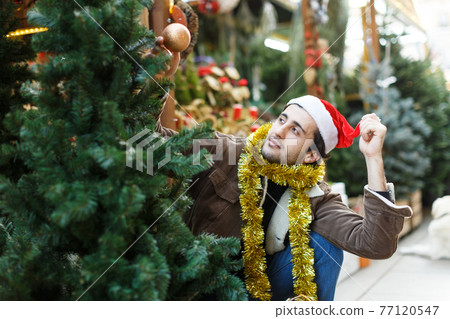 Man choosing decorations and Christmas tree at Christmas market 77120547