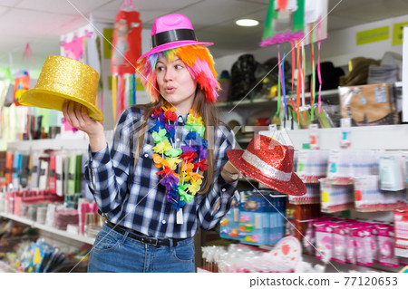Young woman choosing funny headdresses Young woman choosing funny headdresses 77120653