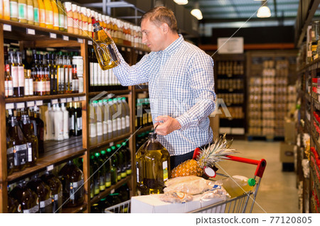 Portrait of man buying olive oil in supermarket 77120805