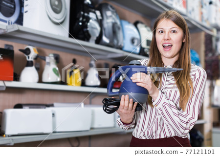 Happy woman customer choosing modern steam cleaner Happy woman customer choosing modern steam cleaner 77121101
