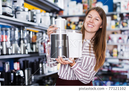 Salesgirl suggesting kitchen machine in household store Salesgirl suggesting kitchen machine in household store 77121102