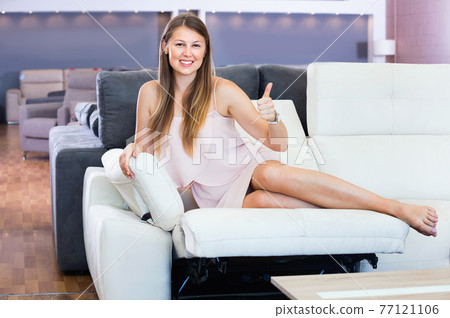 Portrait of woman buyer sitting barefoot on the sofa in furniture shop Portrait of woman buyer sitting barefoot on the sofa in furniture shop 77121106