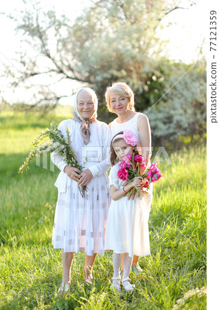 Caucasian granny in white dress with daughter and granddaughter outside. Caucasian granny in white dress with daughter and granddaughter outside. 77121359