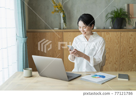 A woman checking her smartphone during remote work 77121786