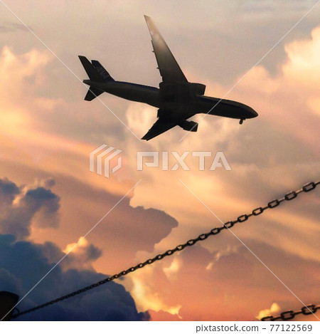 Airplane flying in the calm sunset sky 77122569