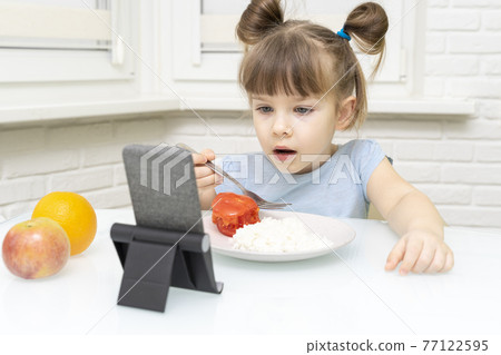 child girl eating lunch and watching cartoons 77122595