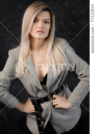 Portrait of blonde woman in gray jacket, black top and leather skirt 77122654
