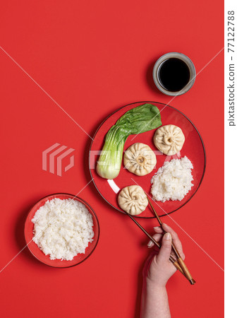 Eating with chopstick chinese steamed food, top view on a red background. 77122788