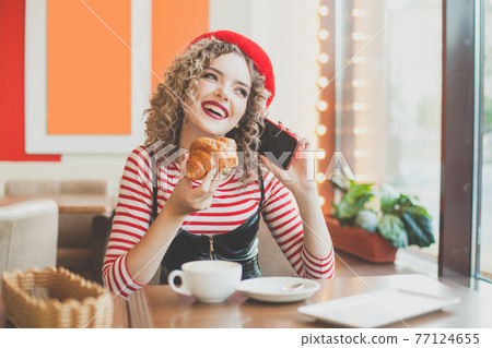 Young woman laughing, chatting and using smartphone in cafe 77124655