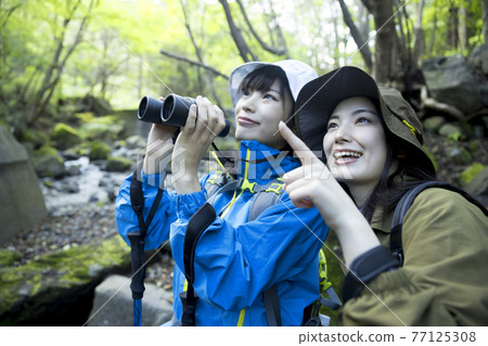 Two young women doing bird watching Two young women doing bird watching 77125308