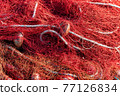 Red fishing nets with ropes and floats. Close-up shot, perfect image for aquaculture, intensive fishing and environmental protection. 77126834