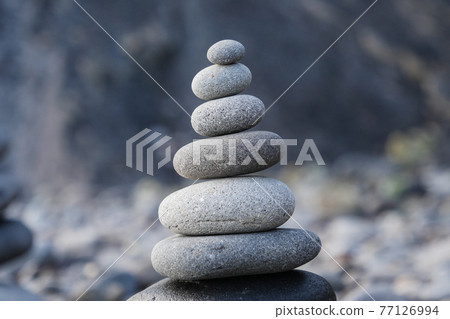 Stone piles made along a beach and the sea in the background Stone piles made along a beach and the sea in the background 77126994