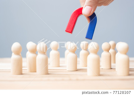 Business man hand holding magnet and pulling man wooden figure from the crowd employee. Business, Human resource management, Recruitment, Teamwork, strategy, toxic people and leadership Concepts Business man hand holding magnet and pulling man wooden figure from the crowd employee. Business, Human resource management, Recruitment, Teamwork, strategy, toxic people and leadership Concepts 77128107