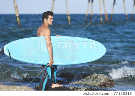 Surfer man holding surfboard on background sea scape, sand beach coastline. Surfer man holding surfboard on background sea scape, sand beach coastline. 77128318