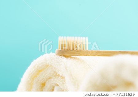 An eco-friendly natural bamboo toothbrush lies on a towel against a blue background. Healthcare, copy space An eco-friendly natural bamboo toothbrush lies on a towel against a blue background. Healthcare, copy space 77131629