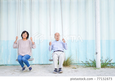 Senior riding a swing with a couple 77132873