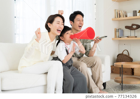 A family of three parents and children watching sports on TV 77134326