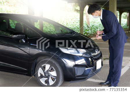 A man in a mask checking a car 77135354