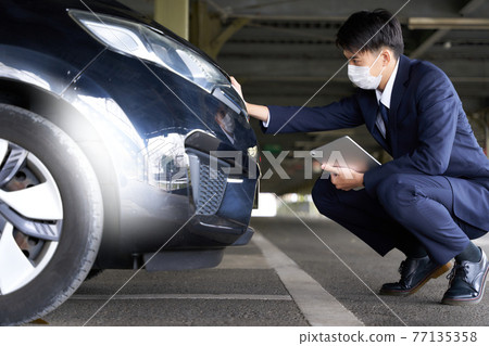 A man in a mask checking a car A man in a mask checking a car 77135358