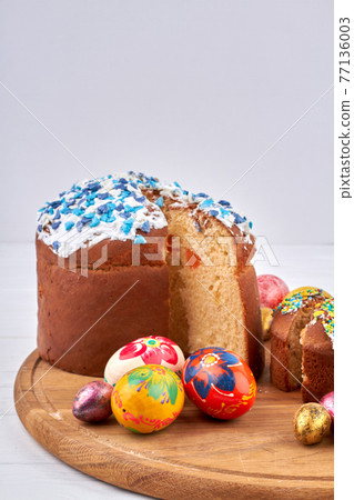 Coloured eggs and homemade easter cakes on white background. 77136003
