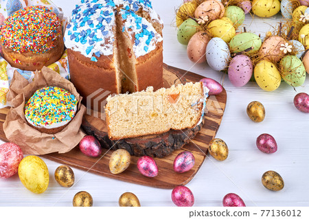 Easter cakes and painted eggs on the wooden board. Easter cakes and painted eggs on the wooden board. 77136012