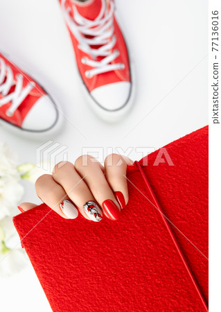 Beautiful young woman's hand with red manicure on gray background 77136016