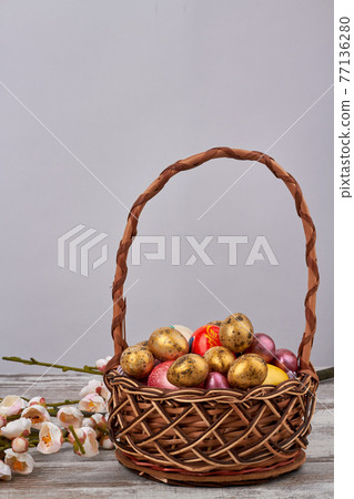 Basket of decoratied easter eggs and flowers. 77136280