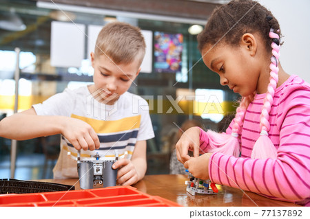 African girl and caucasian boy creating toys. African girl and caucasian boy creating toys. 77137892
