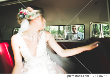 Beautiful newlywed couple posing near retro car Beautiful newlywed couple posing near retro car 77138755