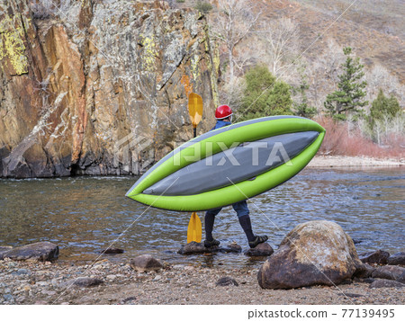 male kayaker is carrying a whitewater inflatable kayak male kayaker is carrying a whitewater inflatable kayak 77139495