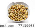 A white bowl with a bunch of salted and roasted pistachio seeds on a white background. Perfect shot for vegan diet,. 77139963