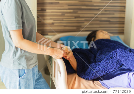 Asian families visit elderly woman patient hand holding hand at the hospital ward. 77142029