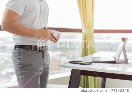 Businessman working laptop and holding cup coffee. Businessman working laptop and holding cup coffee. 77142248