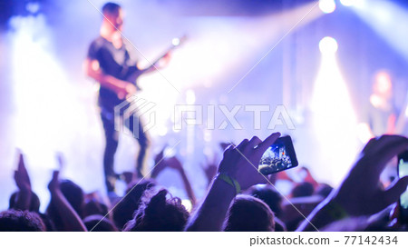 Hands silhouette recording video of live music concert with smartphone Hands silhouette recording video of live music concert with smartphone 77142434