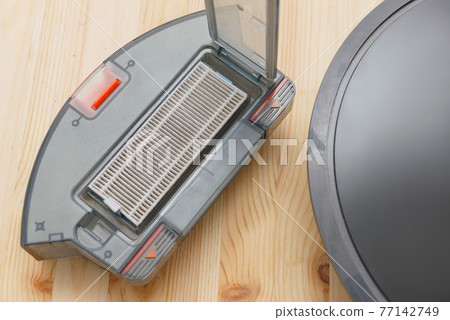 Human takes out a dust container in a robotic vacuum cleaner. 77142749