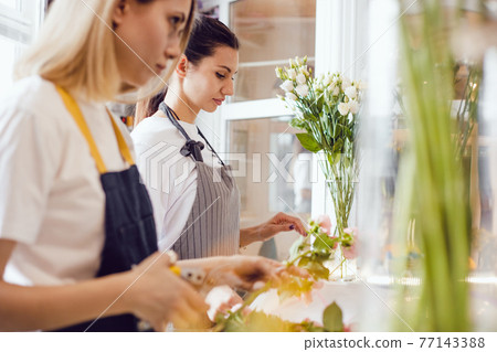 Two women florist at work in a flower shop. 77143388