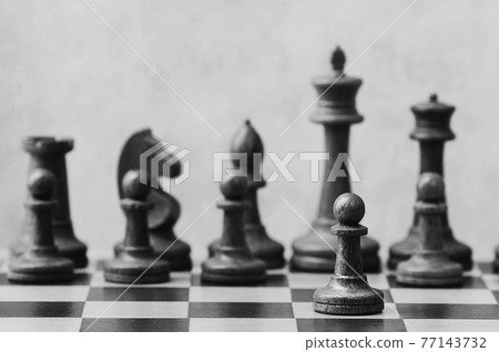 chess on a chessboard - white pawn in front of white chess pieces chess on a chessboard - white pawn in front of white chess pieces 77143732
