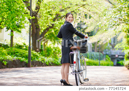 Young woman in a recruitment suit pulling a bicycle Young woman in a recruitment suit pulling a bicycle 77145724