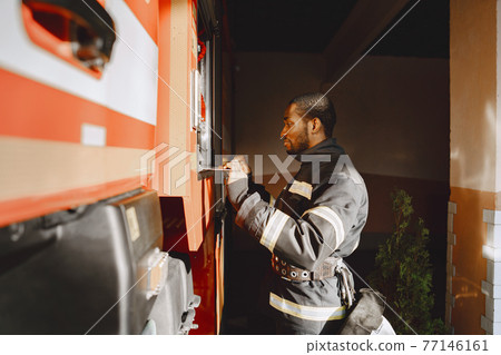 Portrait of a firefighter standing in front of a fire engine 77146161