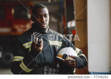 Portrait of a firefighter standing in front of a fire engine 77146262