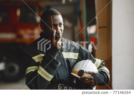 Portrait of a firefighter standing in front of a fire engine Portrait of a firefighter standing in front of a fire engine 77146264